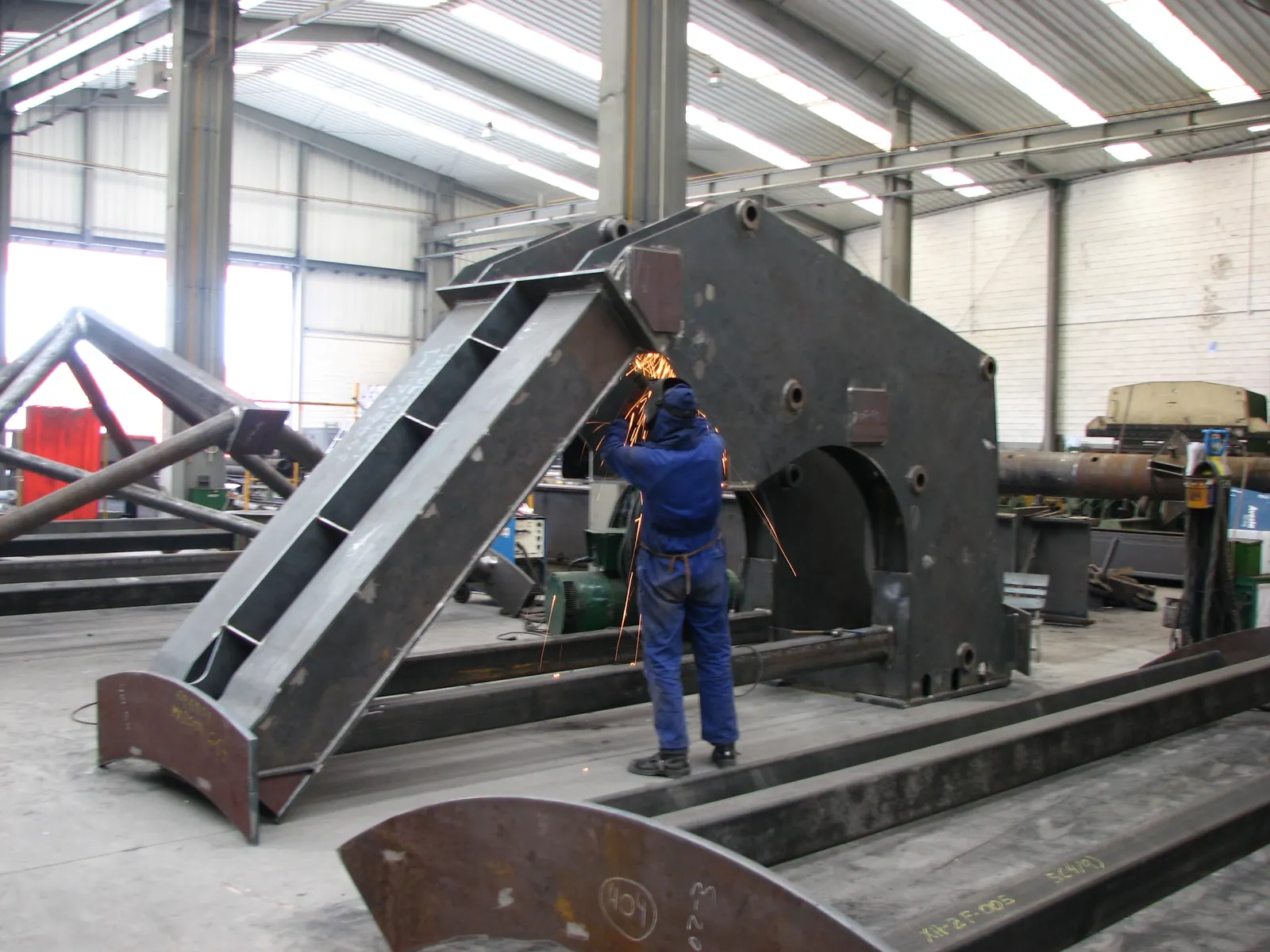 Operario trabajando sobre una estructura metálica de gran espesor en la nave de fabricación